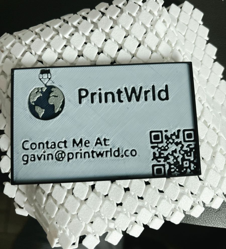 A 3D printed PrintWrld business card with a globe logo, the gavin@printwrld.co email address and a scannable QR code