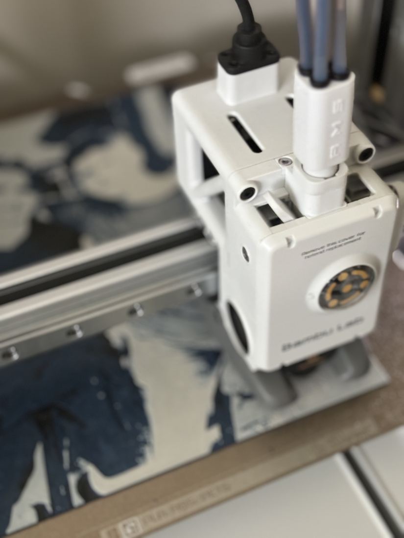 A multi-color 3D printer head printing a navy and white picture